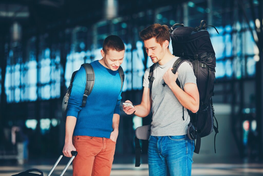 Two friends traveling together. Travelers waiting at the airport departure area for their a flight.